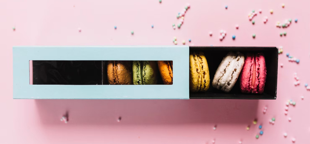 elevated-view-colorful-macaroons-box-pink-background_23-2147957482.jpg